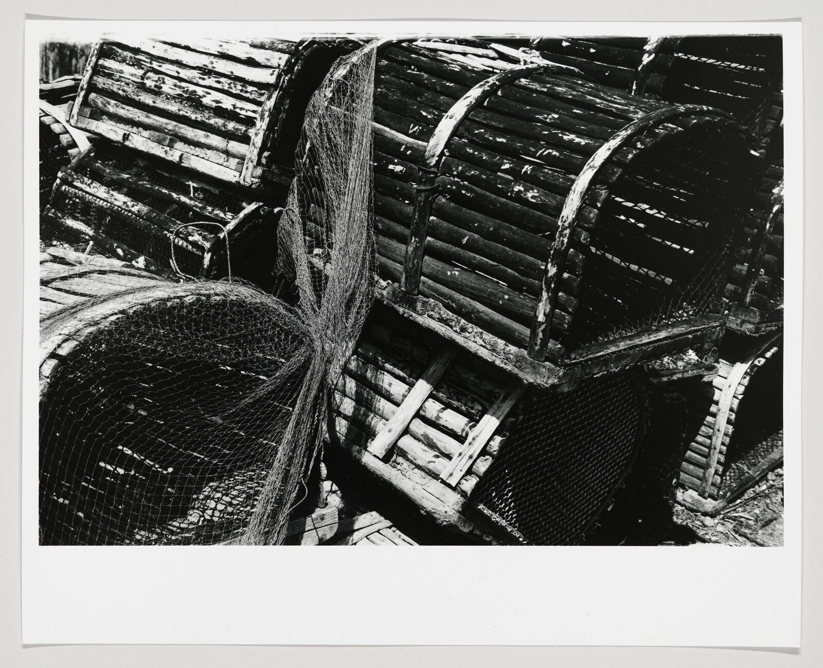 Several stacked wooden lobster pots and tangled fishing net resting on a dock.