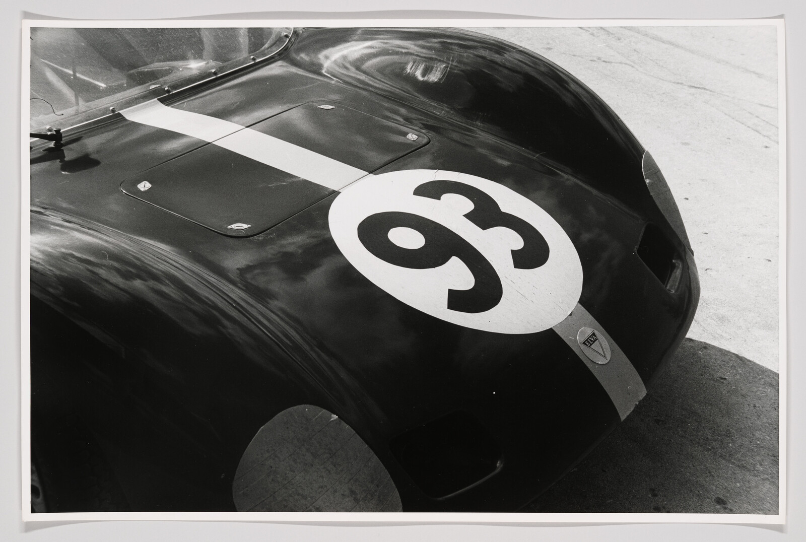 Black race car front with white racing stripe and large number 93 on the hood.