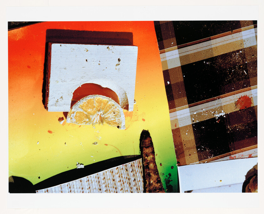 Half an orange slice tucked under a white rectangular block on a colorful gradient surface.