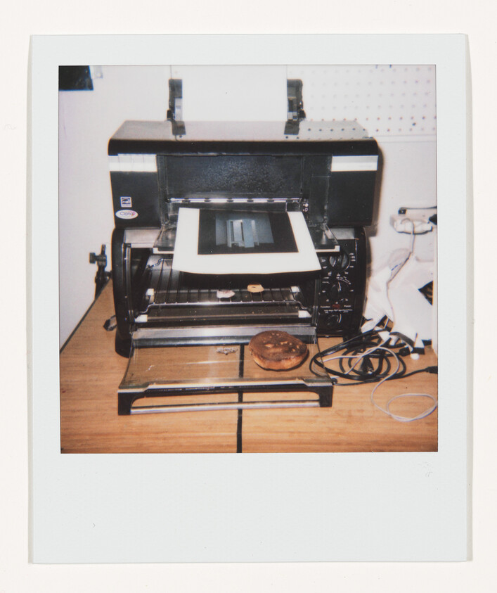 Large black printer on a wooden table with a bagel placed on its output tray.