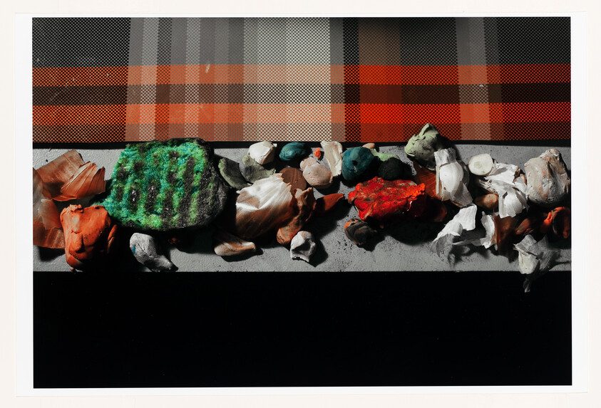A row of colorful crumpled clay and paper pieces lined on a ledge beneath a plaid background.