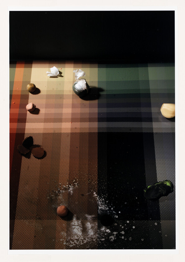 Small clay balls, crumpled paper, and garlic cloves scattered across a multicolored grid surface.