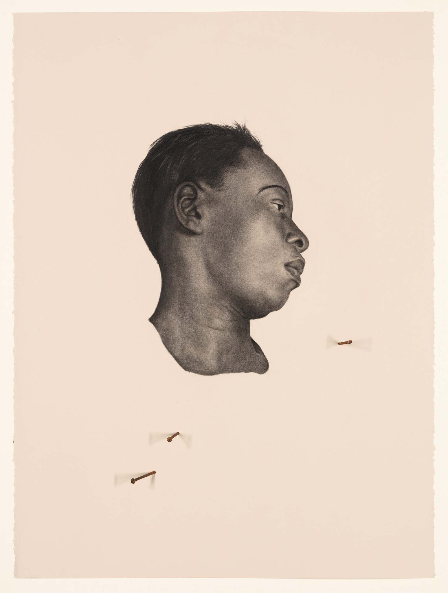 Profile charcoal drawing of a young person's head with three nails pinned nearby.