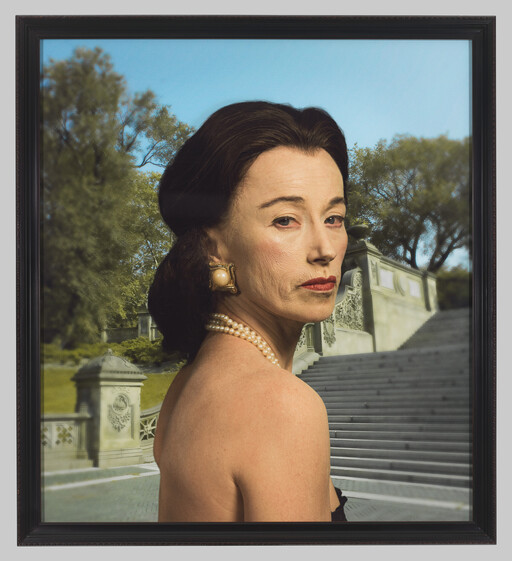 Elegant older woman wearing pearls looks over her shoulder in front of stone steps.