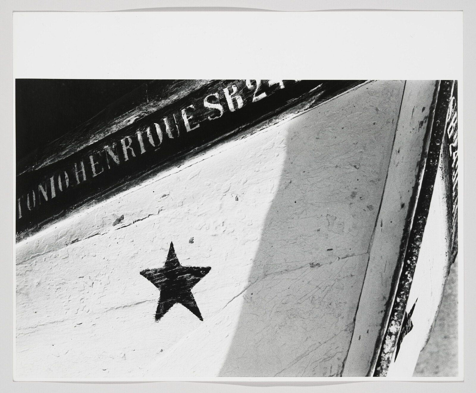 Black five-pointed star painted on a weathered white wooden surface with stenciled lettering above.