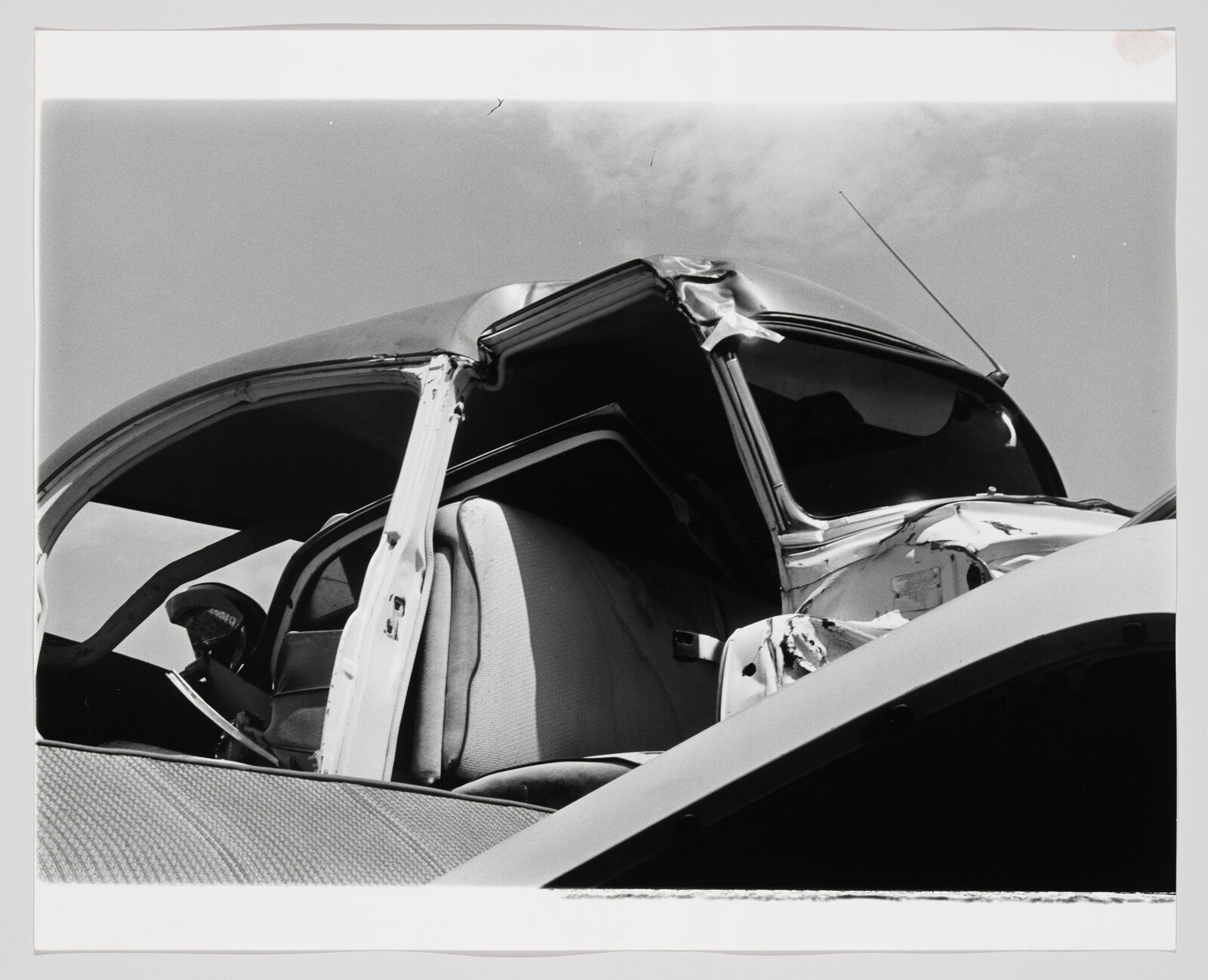 Crumpled vintage car roof and open door exposing the front seat after a severe collision.