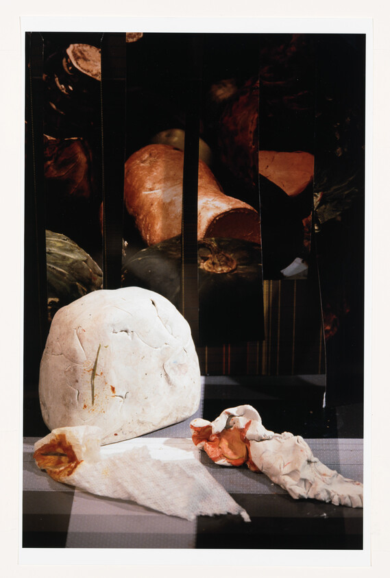 A large white sculpted stone and crumpled clay and fabric pieces arranged on a striped surface.