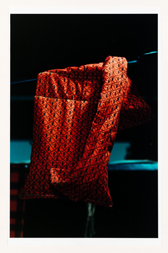 Red patterned scarf draped over a dark metal bar, lit by soft blue light.