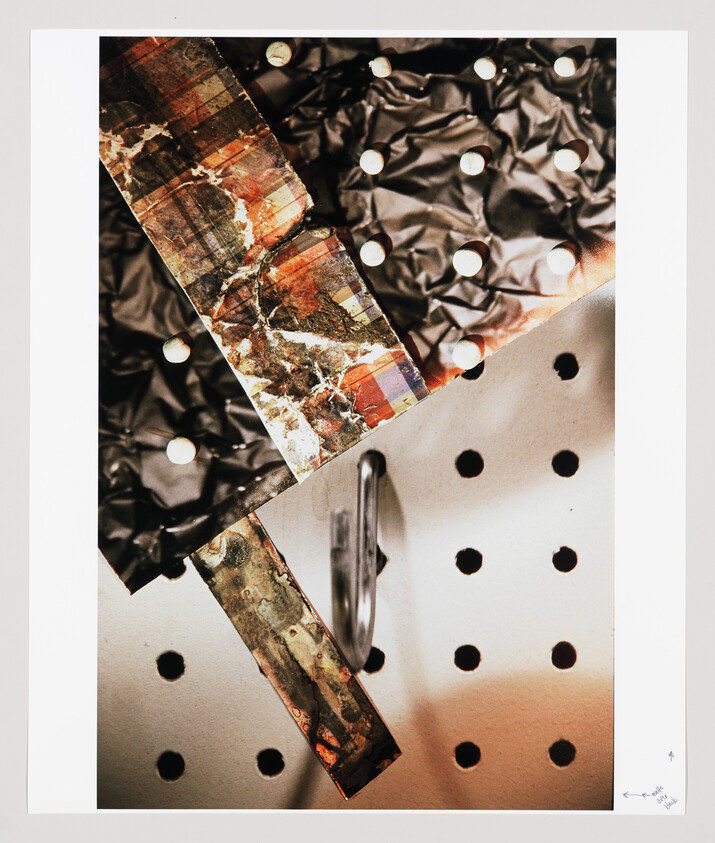 Two weathered decorative strips cross over a perforated pegboard with a metal hook beneath.