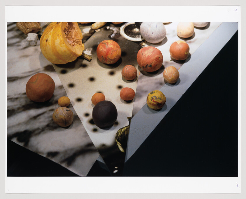 A variety of colorful, spherical objects resembling planets scattered across a surface that is part marble, part dotted pattern, and part solid black, creating a visually intriguing composition that evokes a sense of a miniature solar system on a tabletop.