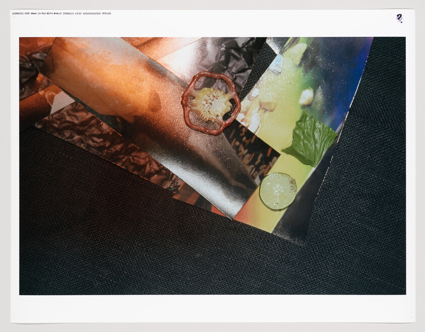 Sliced red pepper ring, lime half, and green leaf arranged on glossy colorful paper over dark fabric.