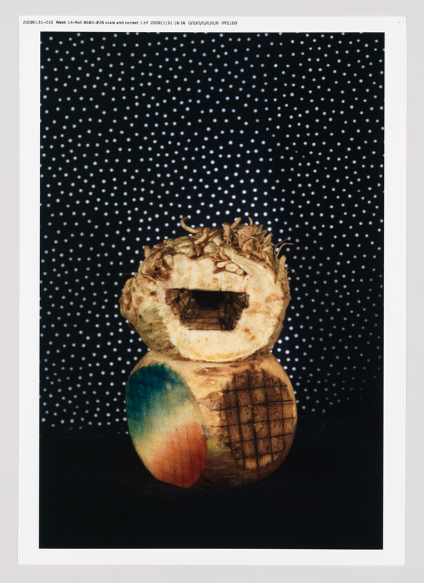 Stacked carved root vegetables, top piece with rectangular cutout and lower piece painted with colorful circle and grid.