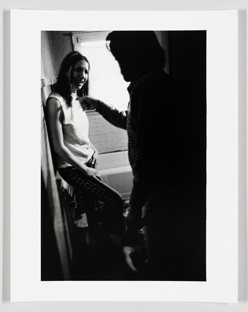 Woman leans against a bathtub looking distressed while a man angrily points at her.