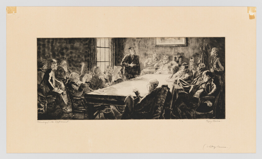 A group of men in formal attire sit around a long table while one man stands speaking.