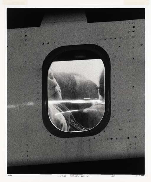 A passenger sleeps against the airplane window while the riveted fuselage frames the view.