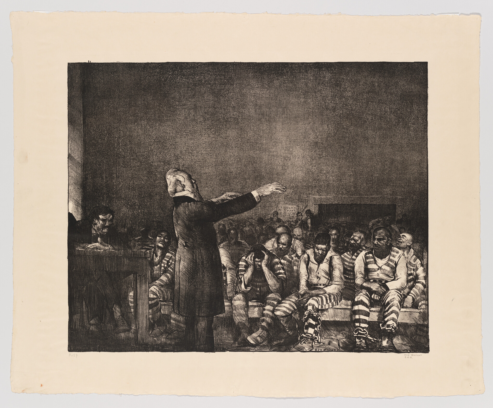 An older man gestures while a group of chained prisoners in striped uniforms sit looking despondent.