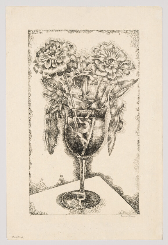 A bouquet of three flowers and leaves arranged in a wine glass on a table.