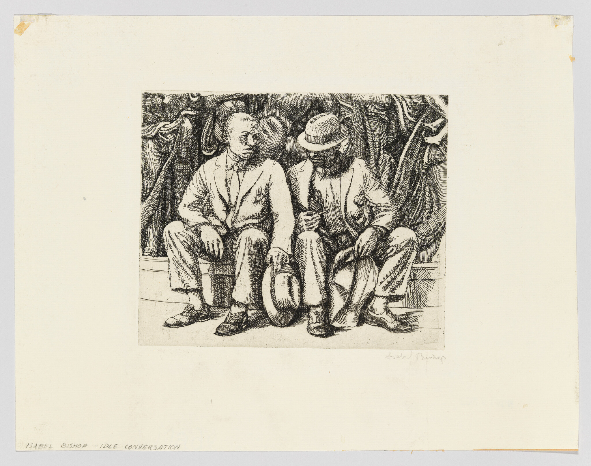 Two men sit on a bench holding hats and talking quietly.