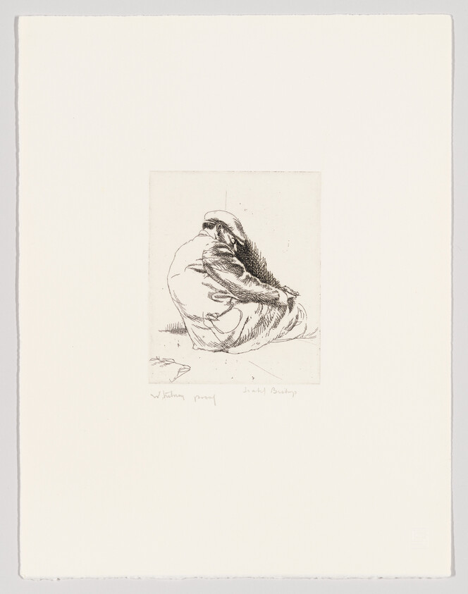 A person wrapped in a cloak sits hunched on the ground facing away.