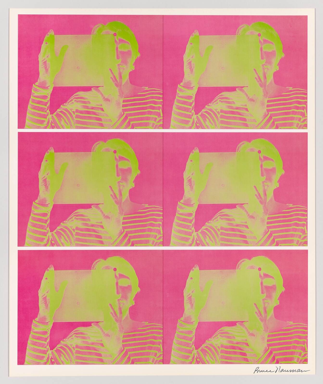 Person holding a translucent rectangular panel over their face in repeated neon pink and green prints.