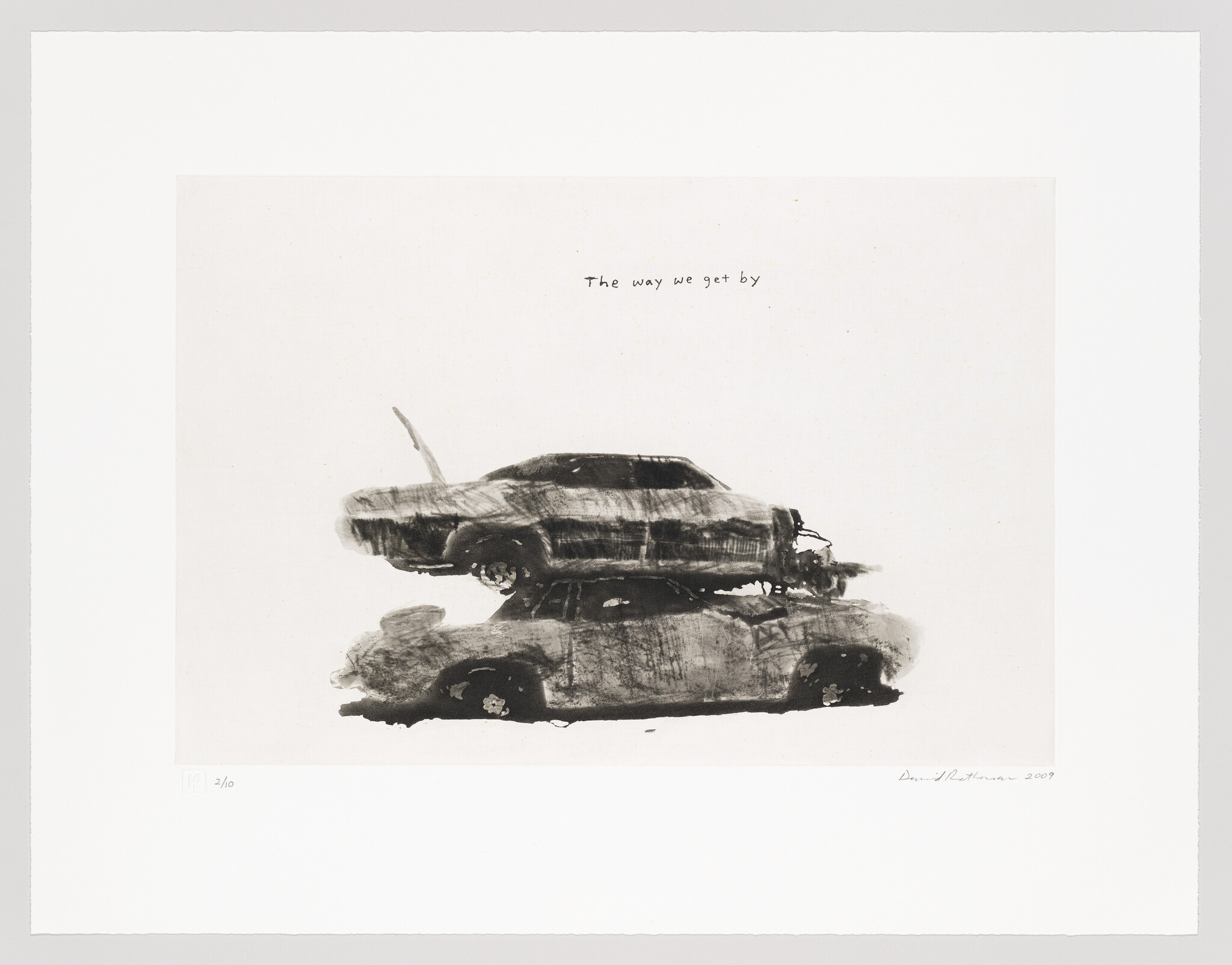 Two worn cars are stacked one atop another with handwritten text "The way we get by."