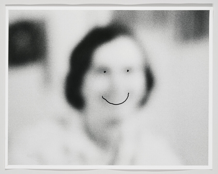 Blurry black-and-white portrait of a person with doodled eyes and a curved smile.