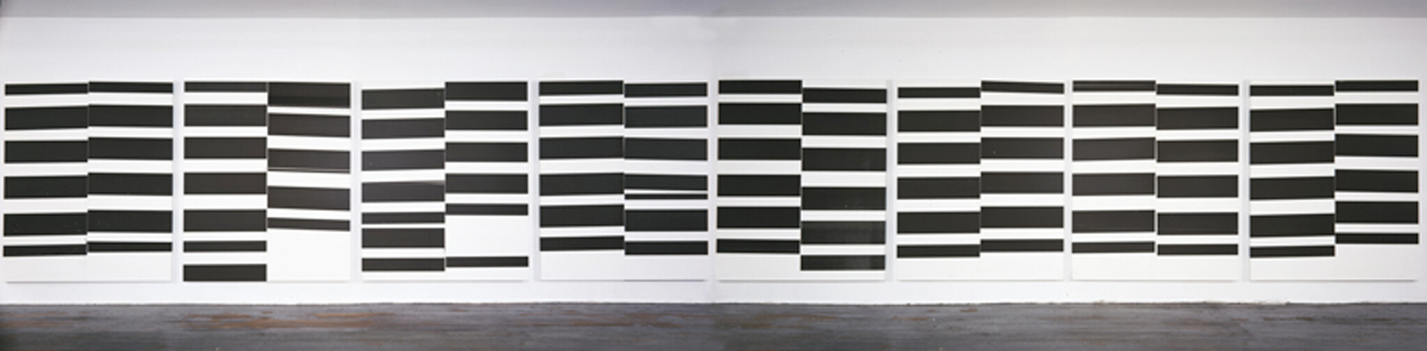 Multiple white panels with staggered horizontal black bars arranged in a grid across a gallery wall.