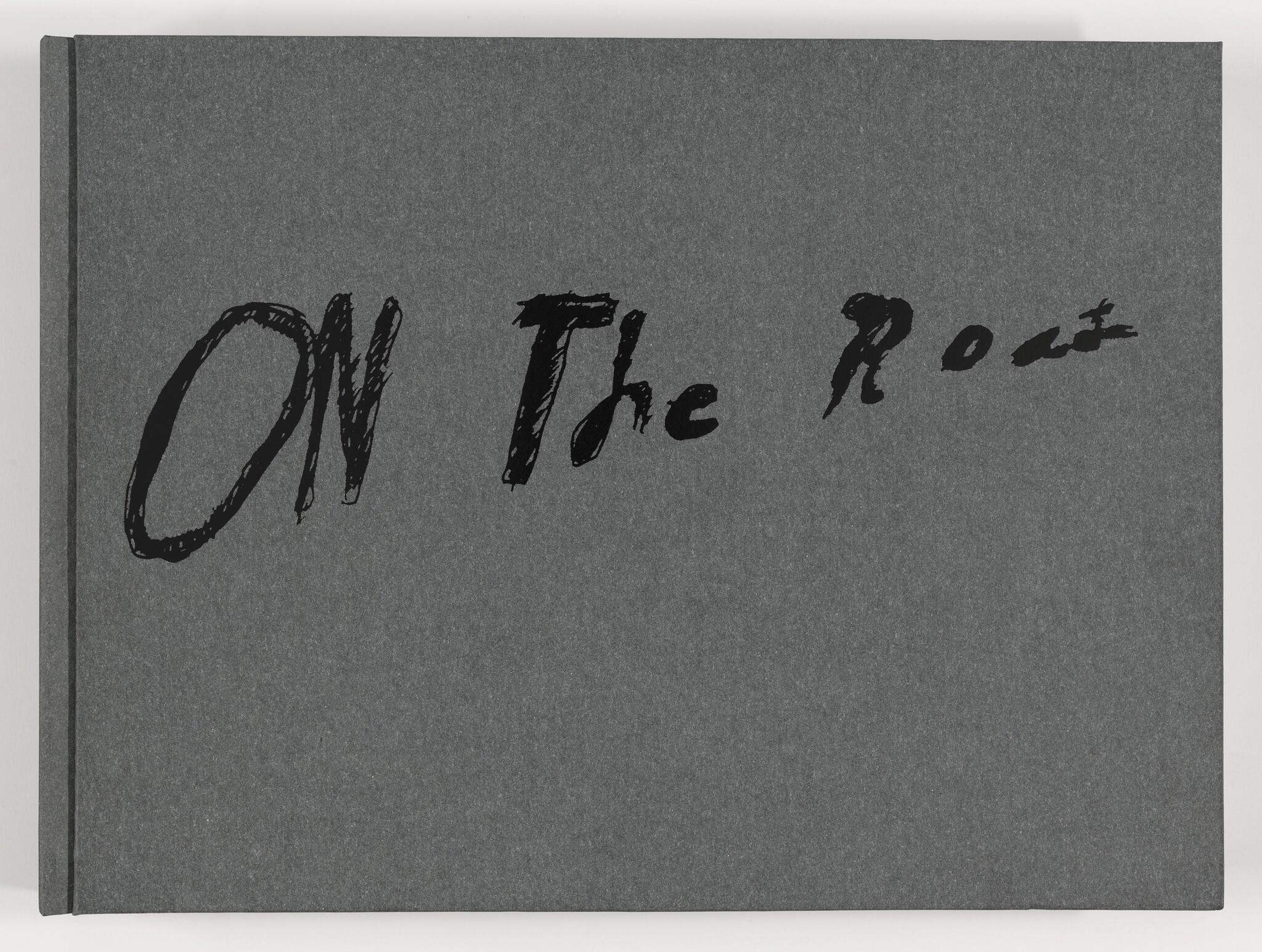 Dark gray book cover with the handwritten title "On the Road" across the front.