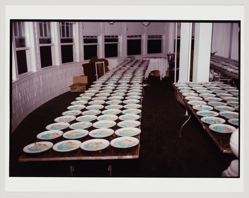Rows of plates with teal centers are neatly arranged on long tables in a large room.
