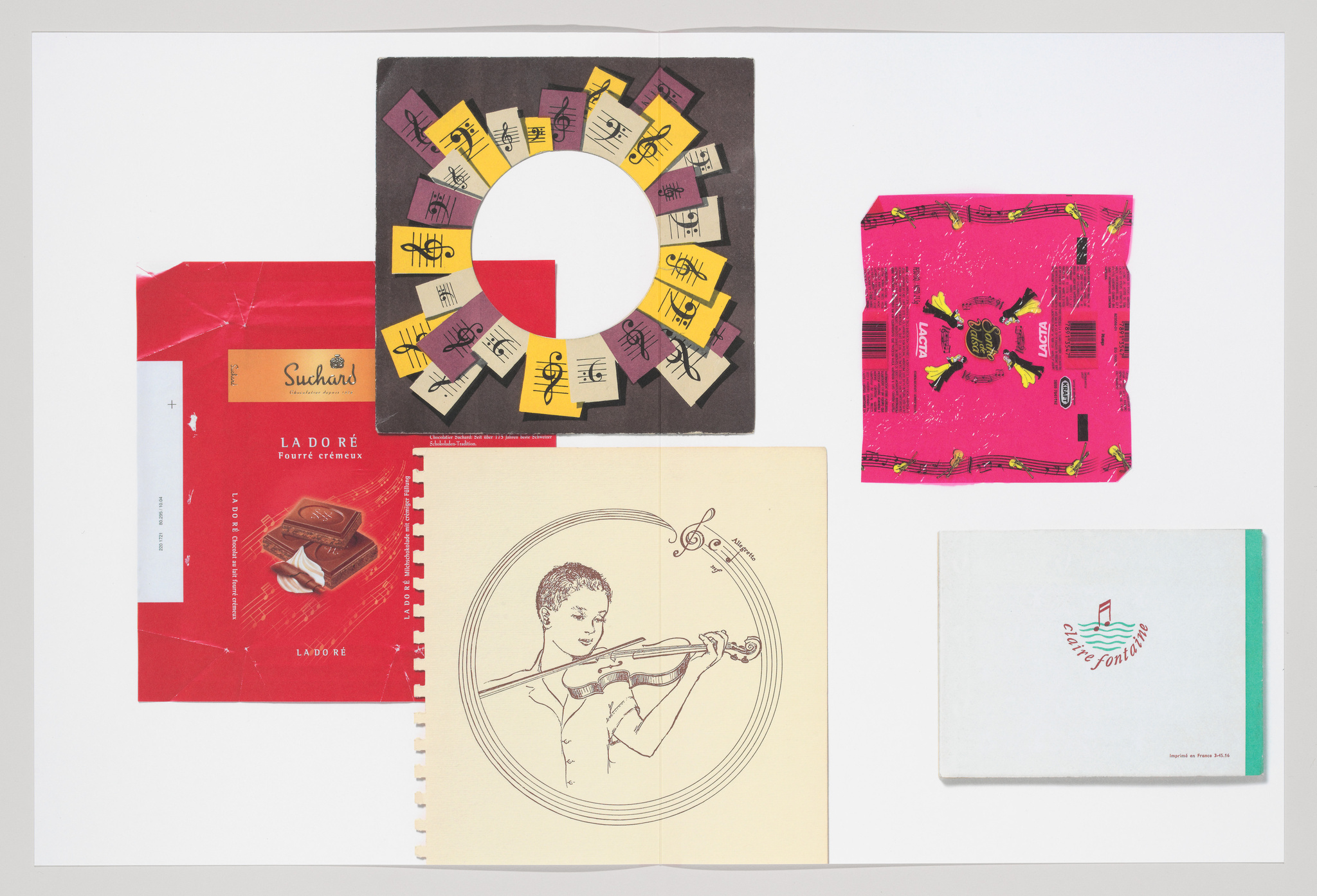 A collection of vintage printed materials laid out on a white surface, including colorful chocolate wrappers, a circular arrangement of music-themed cards, a sketch of a person playing the violin on a notebook page, and a small booklet with a musical note and text on the cover.