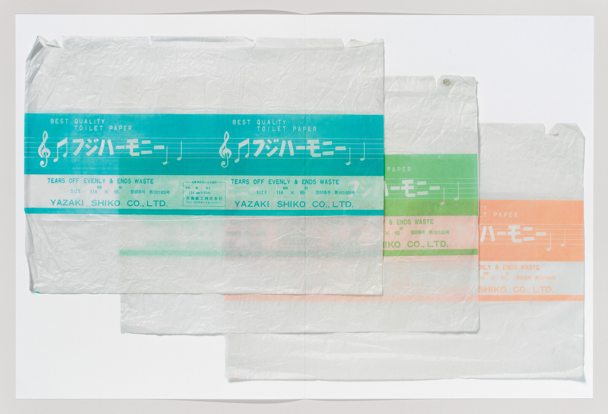Three overlapping toilet paper wrappers with colored musical staff bands and company text.