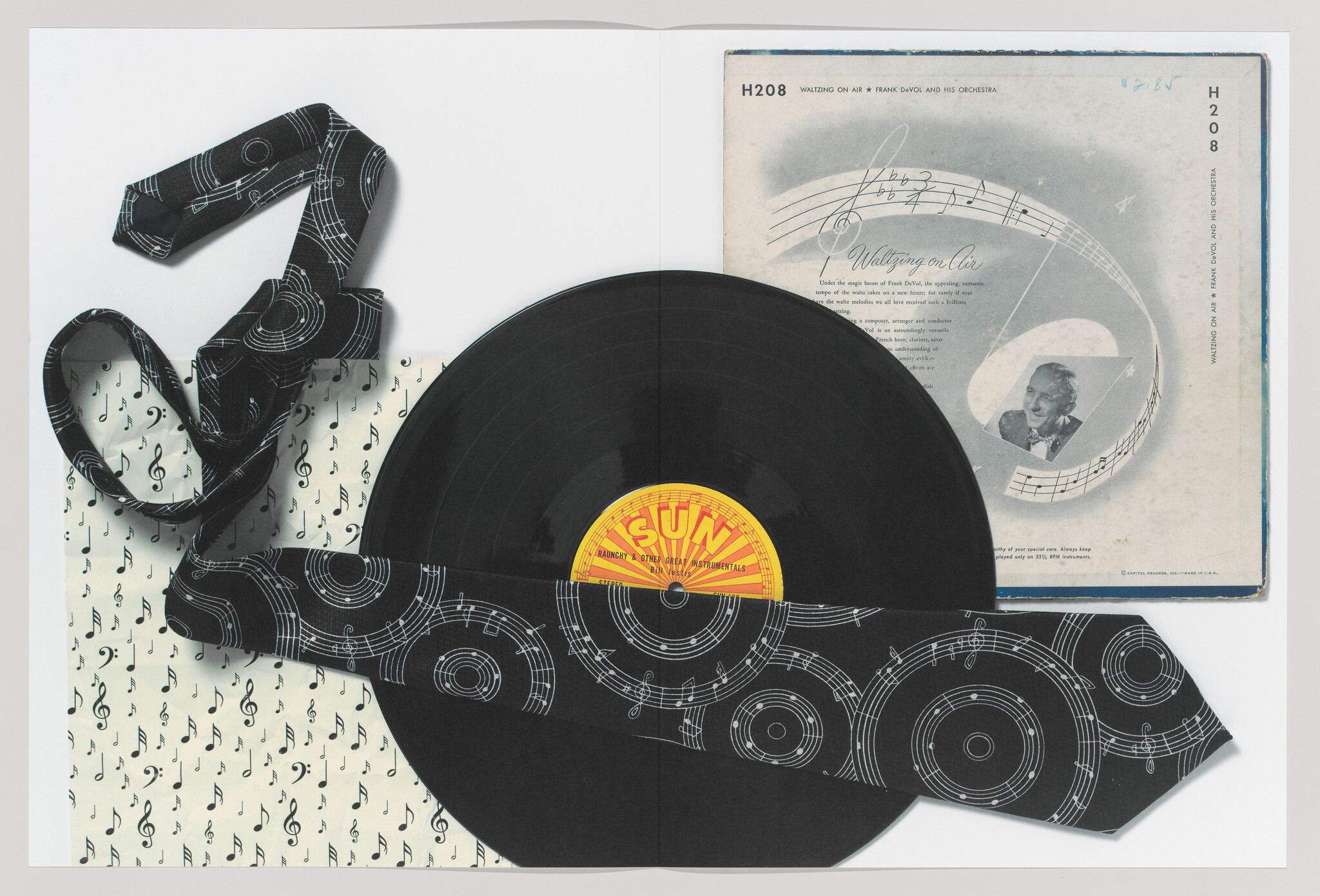 A black vinyl record partially wrapped by a black tie printed with white musical notes.