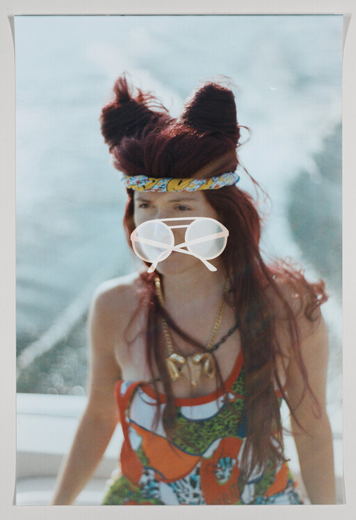 Person with red hair in a colorful dress wearing a patterned headband and white sunglasses.