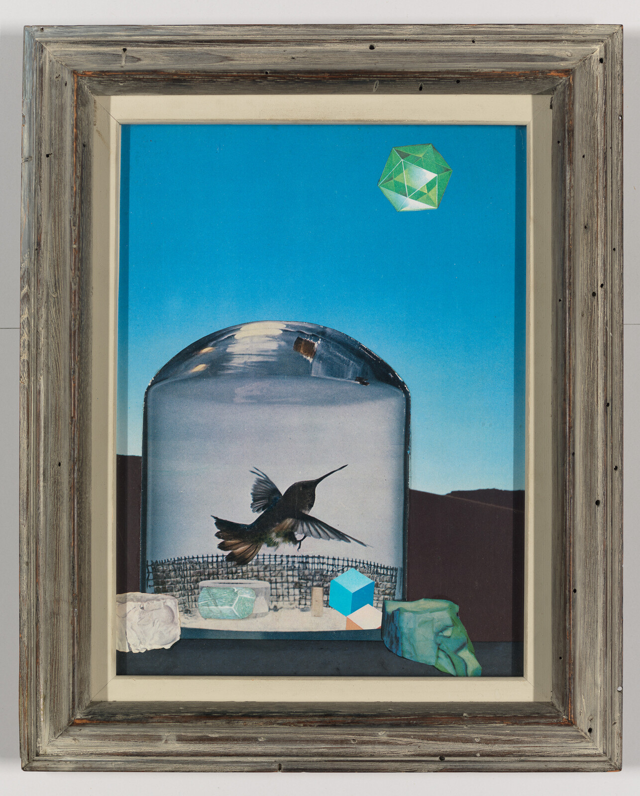 A hummingbird hovers inside a glass dome surrounded by geometric stones and a blue sky.