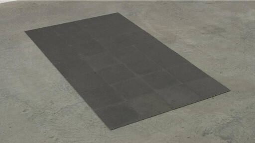 A rectangular dark rubber mat with square tile pattern laid on a concrete floor.