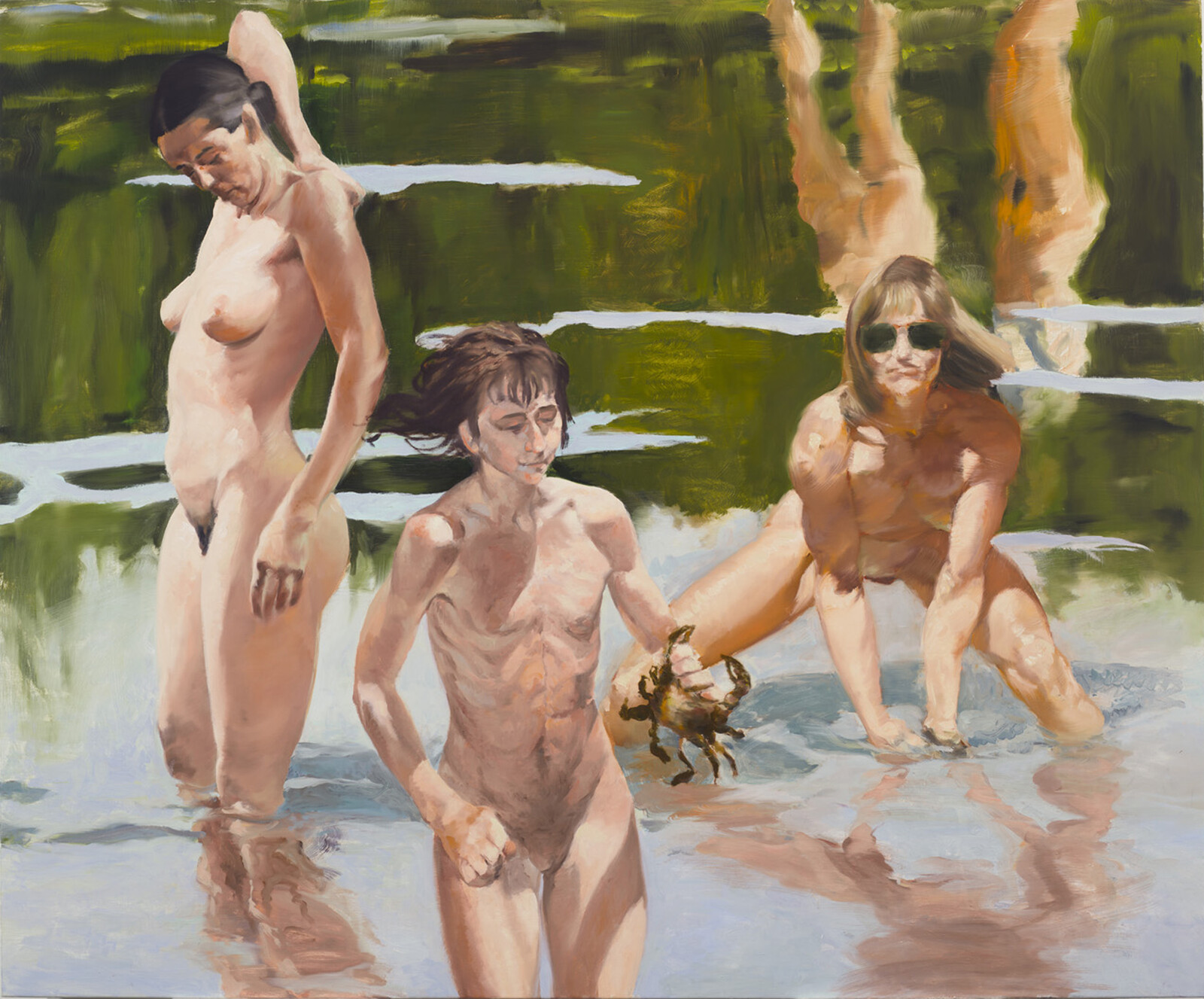 Three people wade in shallow water, one holding a crab, with reflections on the water's surface.