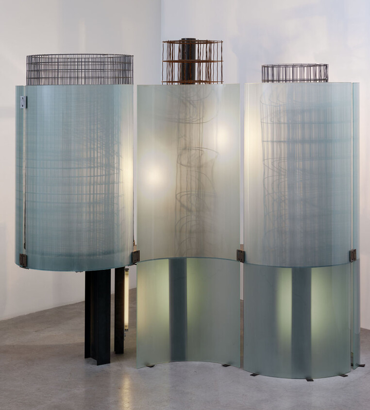 Three tall curved frosted glass panels with internal wire sculptures softly lit from within.