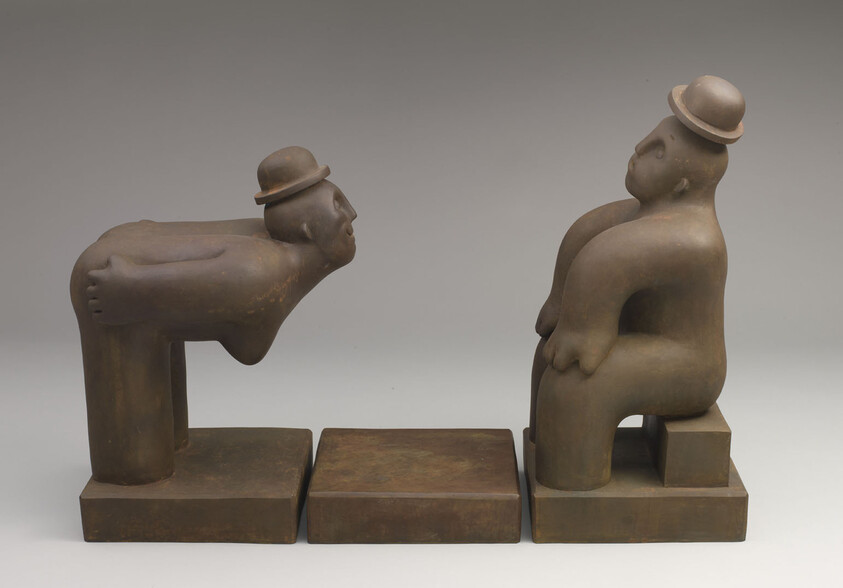 Two brown abstract figures wearing bowler hats face each other across an empty square pedestal.