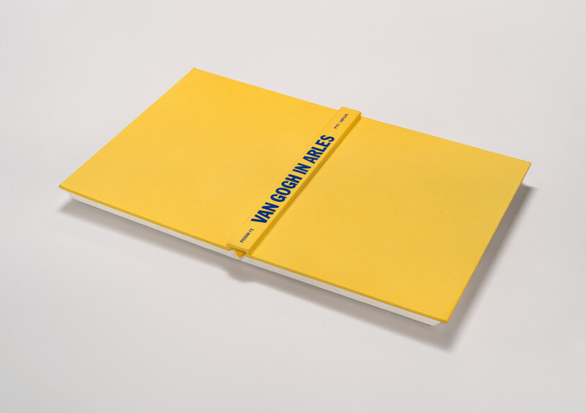 A yellow book is spread opened and the binding reads "Van Gogh in Arles"