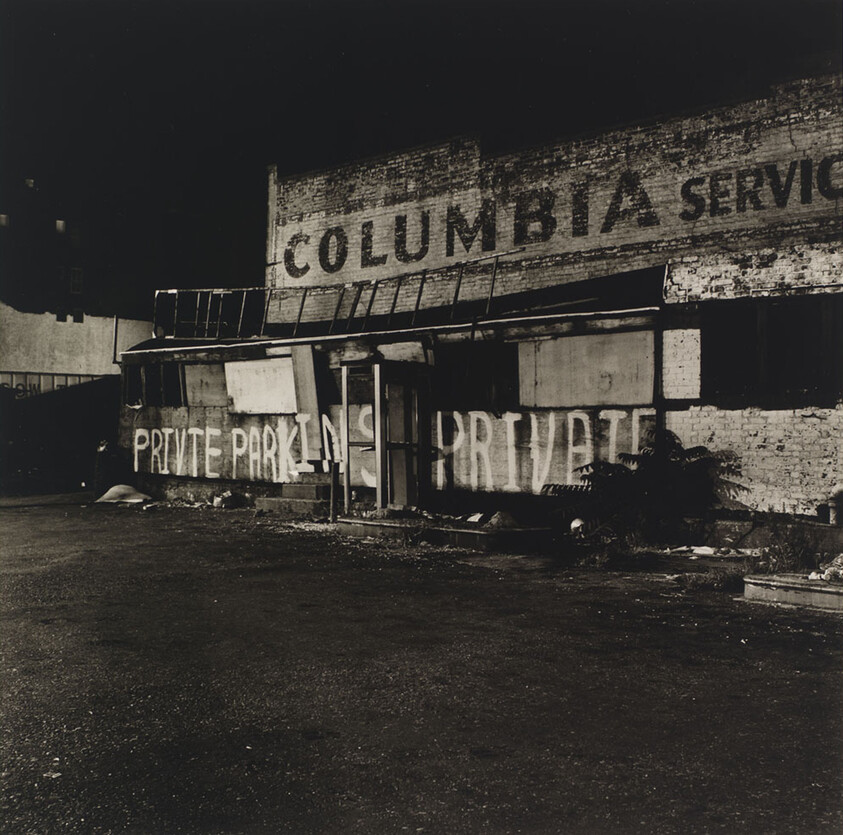 Abandoned brick storefront with faded "Columbia" sign and large "Private Parking" graffiti on boarded windows.