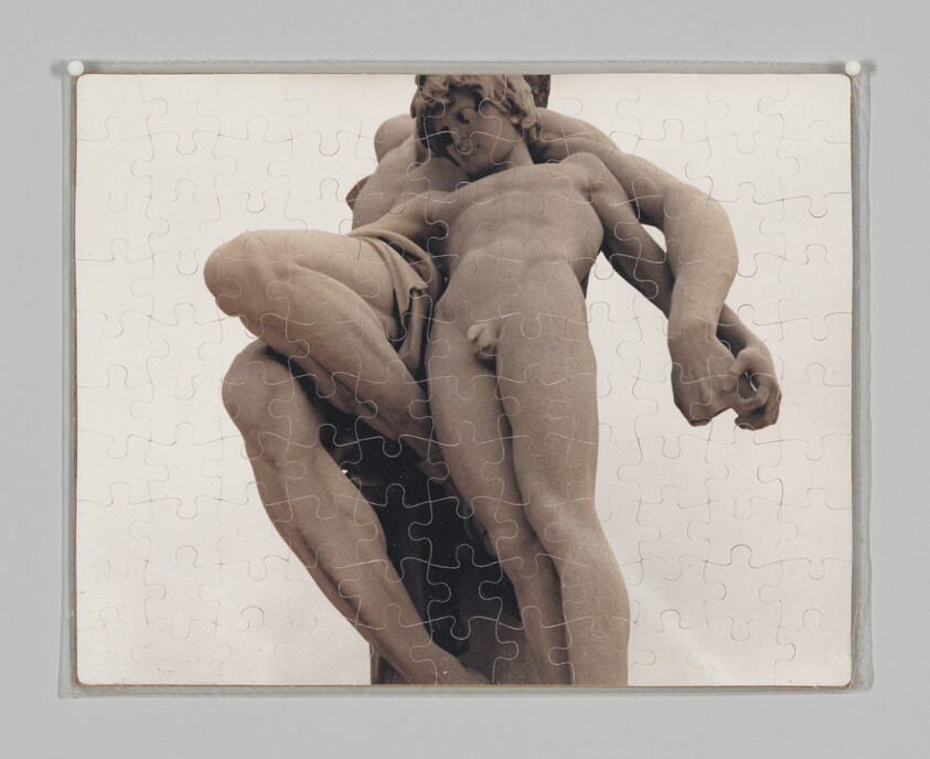 A completed jigsaw puzzle showing a close-up of a classical nude sculpture with intertwined figures.