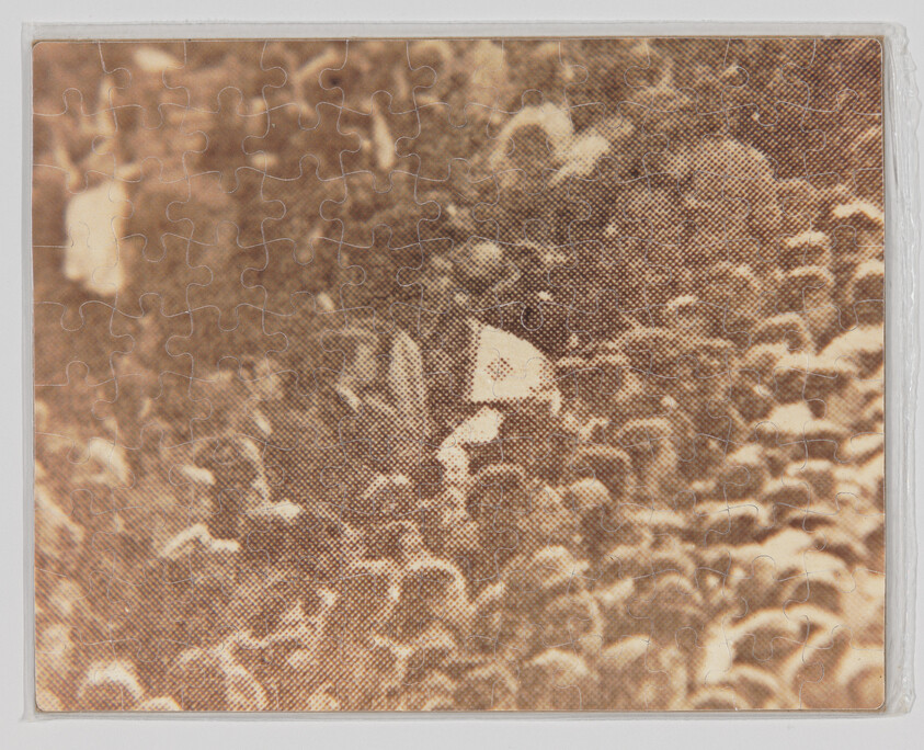 A crowded group of people with one person holding a small white flag above the heads.
