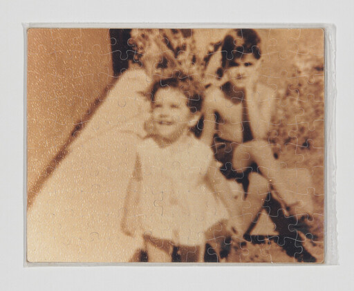 Two children in a sepia jigsaw puzzle, a young girl in a dress sitting in front.
