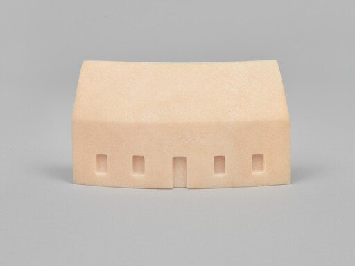 Small smooth beige model house with four rectangular windows and a central doorway on gray surface.