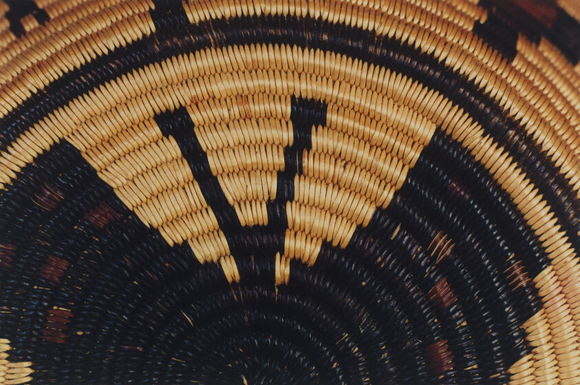 Close-up of a woven basket showing concentric coils and black and natural triangular patterns.