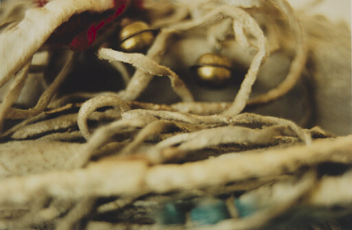 Tangled leather cords with small brass bells and a few turquoise beads resting closely.