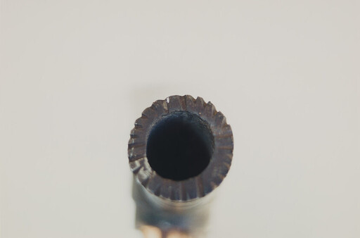 Close-up of a ridged metal cylinder with a dark hollow center.