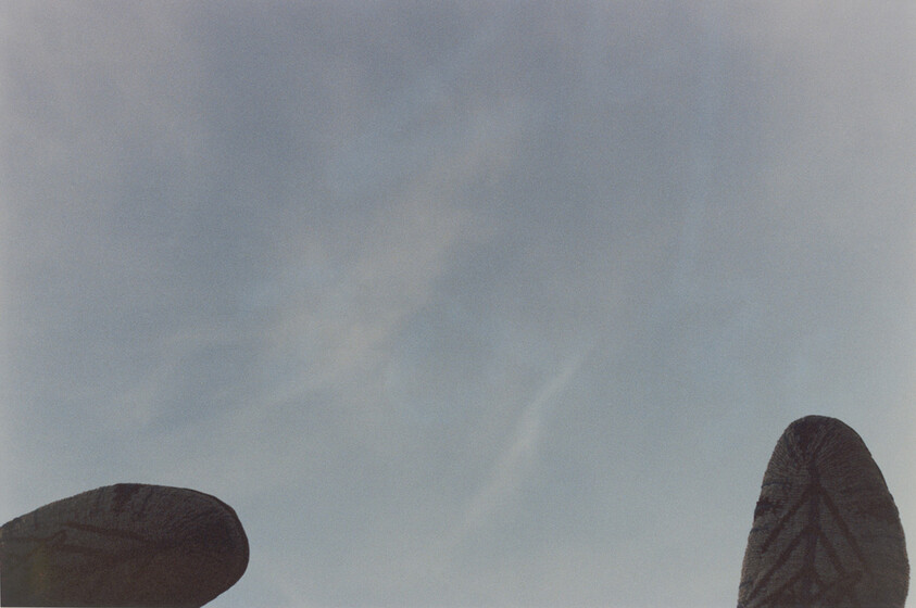 Two carved stone monoliths frame a pale blue sky with faint clouds.