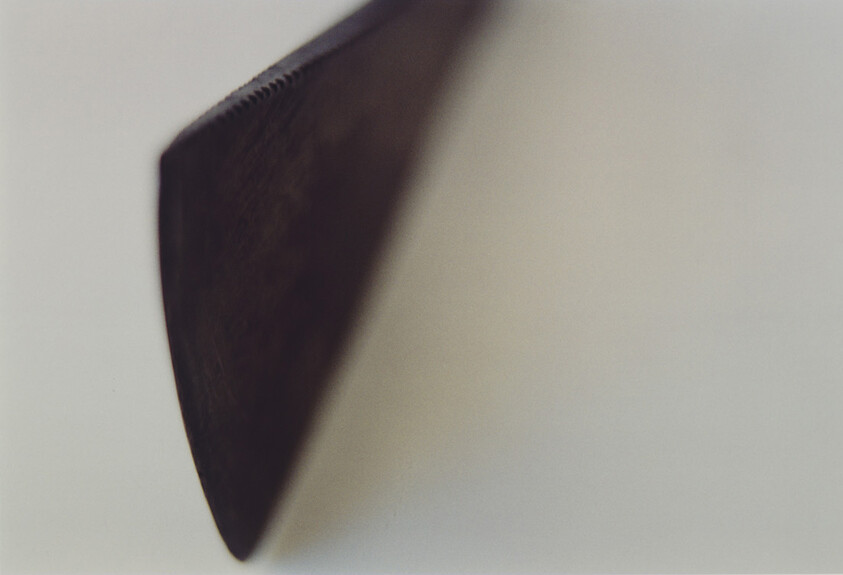 A serrated knife blade edge casts a shadow on a light surface.
