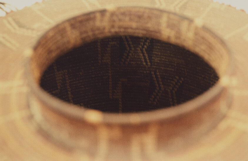 Close-up of a guitar sound hole showing the dark patterned interior and wooden edges.